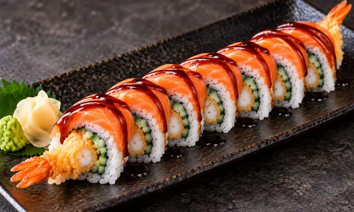 Salmon-topped shrimp tempura sushi roll served with wasabi and pickled ginger